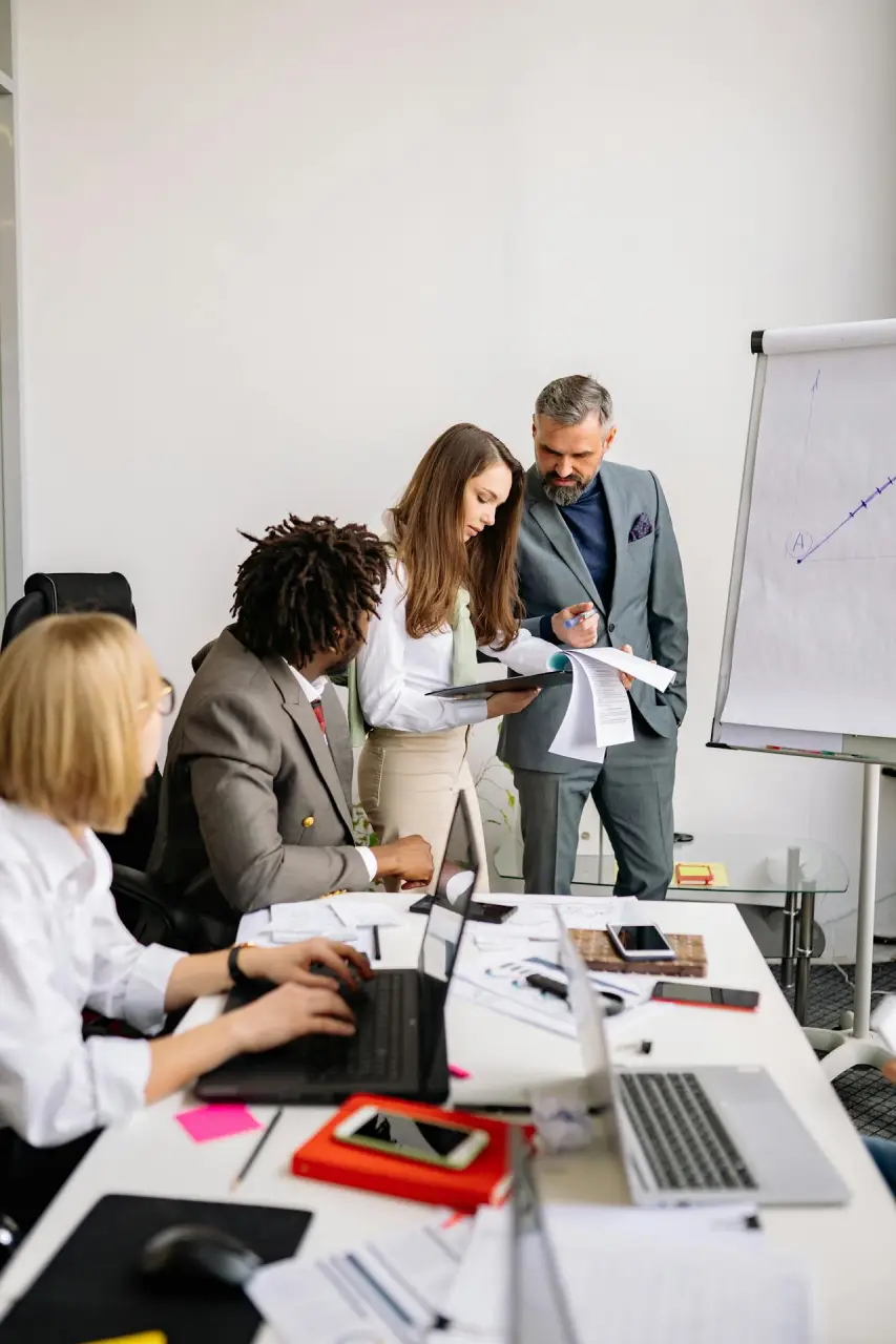A group of business professionals engaged in a discussion around a conference table in a modern meeting room